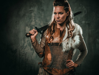 Viking woman with cold weapon in a traditional warrior clothes