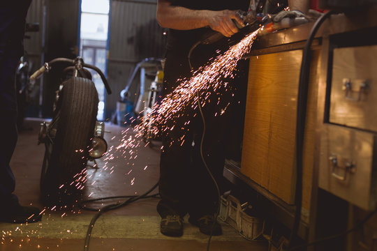 Unrecognizable worker cutting metal in garage