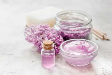 lilac cosmetics with flowers and spa set on stone table background
