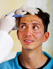 Naklejka premium Closeup of a handsome young man, receiving facial cosmetic treatment injections, doctors hand with glove holding syringe