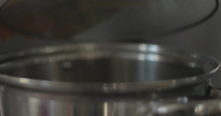 Cook lifts lid off soup pot