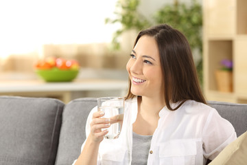 Woman thinking and holding a glass of water