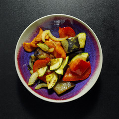 grilled vegetables in a bowl on black background