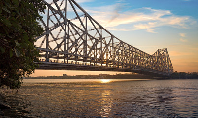 Historic Howrah bridge at sunrise with moody sky. Howrah bridge is a cantilever bridge on river Hooghly at Kolkata, India.