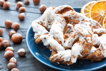Bavarian cream puff with crushed hazelnut and lemon fondant on a blue plate. In the background a cup of tea and slices of dried oranges