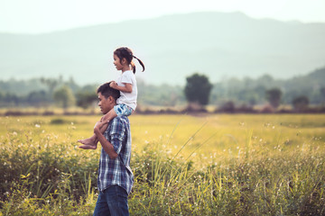 Father and daughter having fun to play together in the cornfield and child riding on father's shoulders in vintage color tone