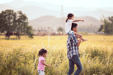 Father and daughter having fun and playing together in the cornfield and child riding on father's shoulders in vintage color tone