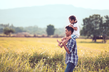 Father and daughter having fun to play together in the cornfield and child riding on father's shoulders in vintage color tone