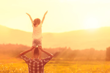 Silhouettes of father and daughter playing together in the cornfield at sunset.
