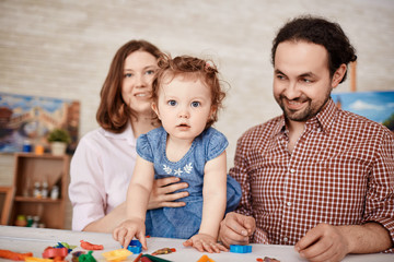 Happy family posing for portrait while playing with little daughter at home