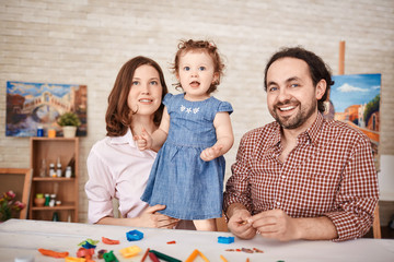 Obraz premium Portrait of happy family posing for photo and smiling while playing with little daughter at home