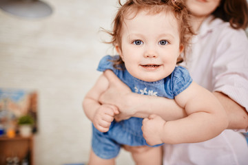 Fototapeta premium Portrait of cute little girl smiling looking at camera on mothers arms