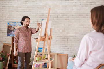 Portrait of professional artist painting portrait of young model in personal art studio