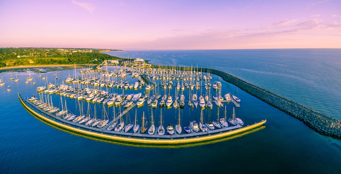 Aerial panoramic view of moored sailboats, breakwater, and Melbourne coastline at beautiful sunset