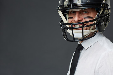 Fototapeta na wymiar Closeup portrait of confident middle aged businessman with army paint on his face wearing helmet and smiling at camera against grey background, copy space to the left