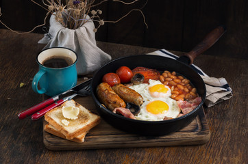 English breakfast with sausages, bacon, fried eggs, beans, toast, coffee