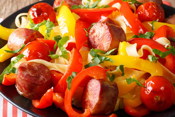 Delicious food: stewed pepper with fried sausages, noodles and tomatoes close-up. horizontal