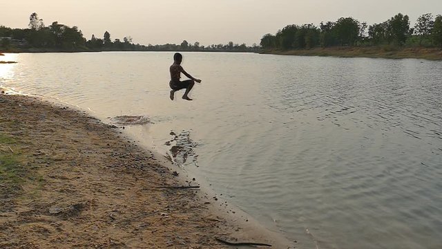 Young kid jumping to swimming in the lake.