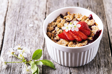 Strawberry blackberry crumble with oatmeal crispy crust on vintage rustic wooden table. Healthy breakfast. Summer baking. Diet. Selective focus 