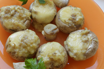 Mushrooms baked with cheese in an orange dish. Homemade