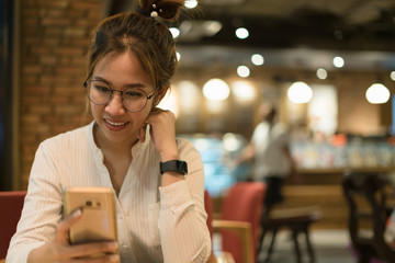 Charming asian woman in casual using cellphone ,sitting and looking in coffee cafe shop with...