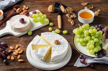 Cheese Brie with grapes and nuts on a wooden board