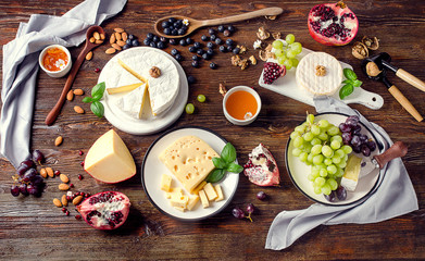 Cheese with grapes and nuts on dark wooden board