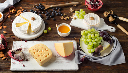 Cheese with grapes and walnuts on dark wooden board