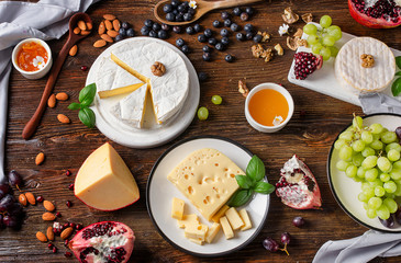 Cheese Brie with grapes and nuts on dark wooden board