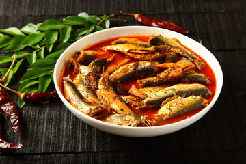 Spicy sardine curry on wooden background.