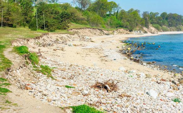 Beach erosion. Erosion has removed large parts of the soil into the sea, leaving stones and steep shorelines.