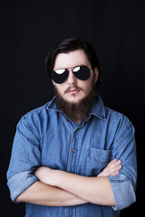 Portrait of a young bearded man posing on black background