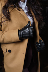Female hands in black leather gloves on lapels wool coat camel