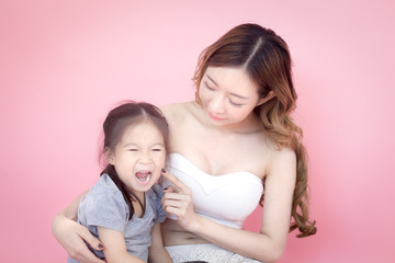 woman hodling kid with sad emotion, isolated on pink background.