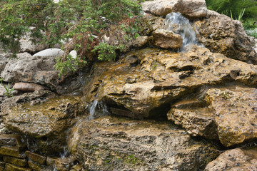 Composition of small artificial waterfall and stones in park