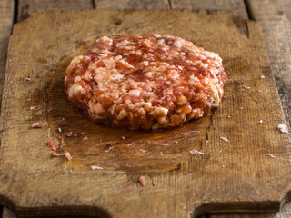 Raw minced meat in the form of cutlets (round and flat) on the chalkboard