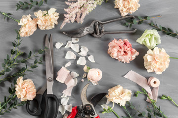 flowers and garden tools. The florist work table with accessories gray background.