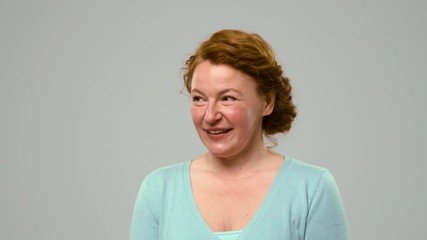 Mid aged red haired woman showing happy emotions, ogling. Foxy mid aged actress smiling, laughing and showing positive emotions in studio,