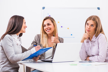 Three businesswomen are having meeting in their office. 