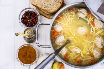 Meat broth with meatballs and spaghetti in a saucepan