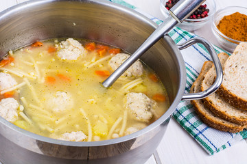 Meat broth with meatballs and spaghetti in a saucepan