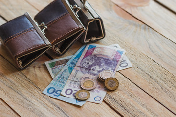 Polish zloty with little wallets on the old wooden background