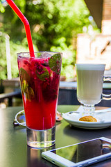 Lemonade with raspberries and mint and coffee latte on a table in a street cafe