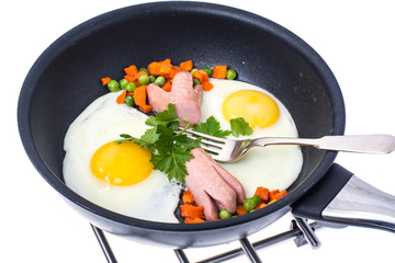 Fried eggs with sausage and vegetables in frying pan on white ba
