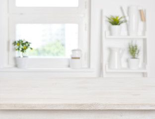 Fototapeta na wymiar Empty bleached wooden table and kitchen window shelves blurred background