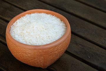 Fototapeta na wymiar Uncooked rice in an earthware on wood table