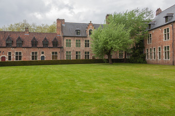 Fototapeta na wymiar View of famous Grand Beguinage of Leuven with green lawn in foreground in spring cloudy day, Belgium