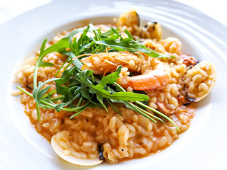 Tasty risotto with Shrimp, fresh herbs vegetables on a white plate