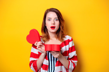 Woman with heart shape box on yellow background