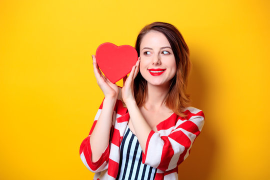 Woman with heart shape box on yellow background